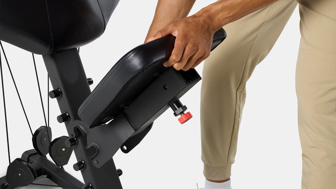 Hands adjusting the BowFlex Xtreme 2 SE Home Gym seat.