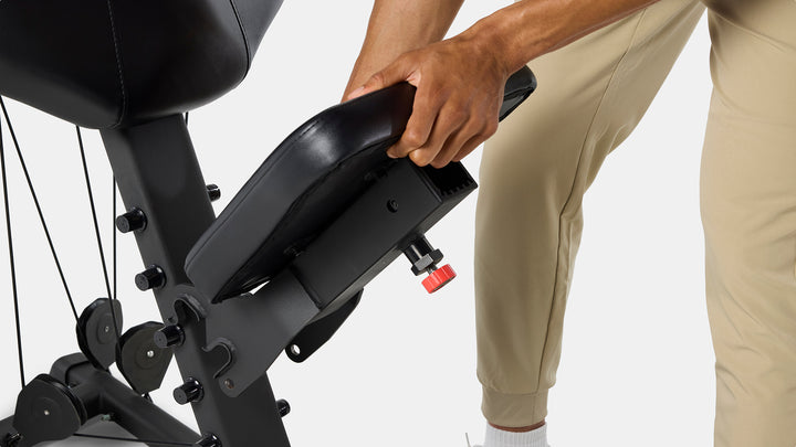 Hands adjusting the BowFlex Xtreme 2 SE Home Gym seat.