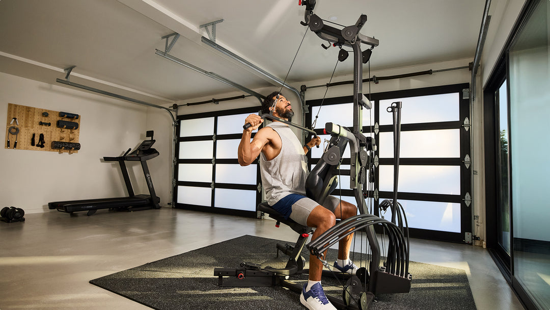 Man using the steel curved lat bar on the BowFlex Xtreme 2 SE in a home gym.