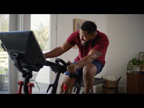 Man exercising on the BowFlex VeloCore Bike in its leaning mode in a home setting.