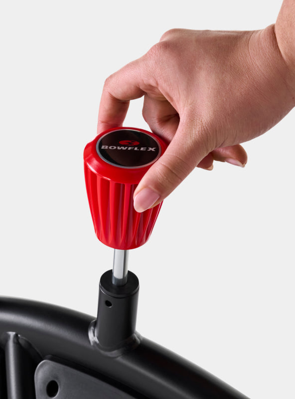 A person's hand on the BowFlex VeloCore Bike 22 resistance level adjustment knob.